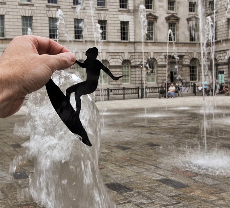 在伦敦萨默塞特宫（Somerset House），麦克尔尝试在这座经典建筑外面的喷泉上，创造纸人冲浪场景。（网页截图）