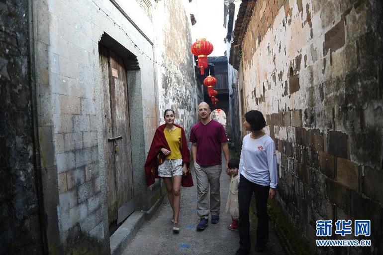  玛丽亚（左一）与外国友人一起走在浙江省金华市汤溪镇寺平村的明清古建筑群中（10月21日摄）。