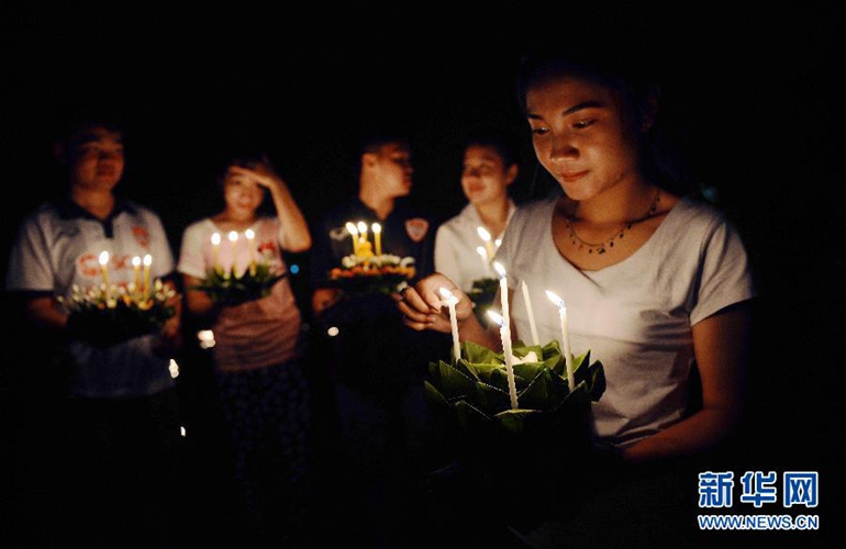  10月27日，在老挝首都万象，当地居民点燃水灯上的蜡烛。新华社发（刘艾伦摄）