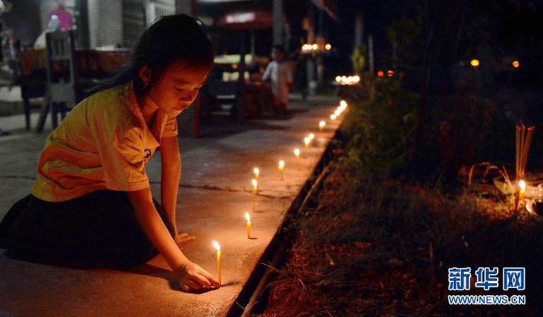 10月27日，在老挝首都万象，一个女孩在家门口点燃蜡烛祈福。