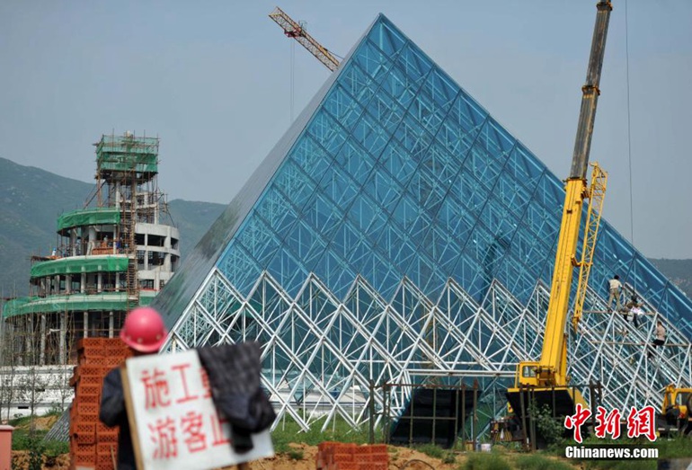 2015年9月8日，位于河北石家庄一影视基地，一座在建的“法国卢浮宫金字塔”吸引了过往市民的眼球。该影视基地位于该市山前大道旁洞沟村东侧，2014年因建造1:1.5比例的山寨版“埃及狮身人面像”，一度成为热点。2015年，该影视基地又在“狮身人面像”两侧建起了山寨“法国卢浮宫金字塔”和“天坛”。（中新社发 翟羽佳 摄